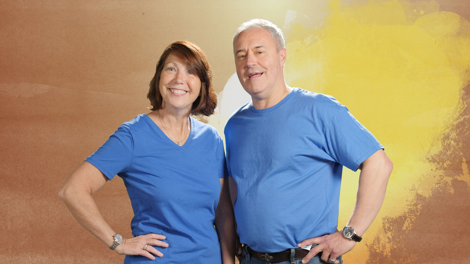 A woman and man wearing blue shirts posing in front of an abstract background